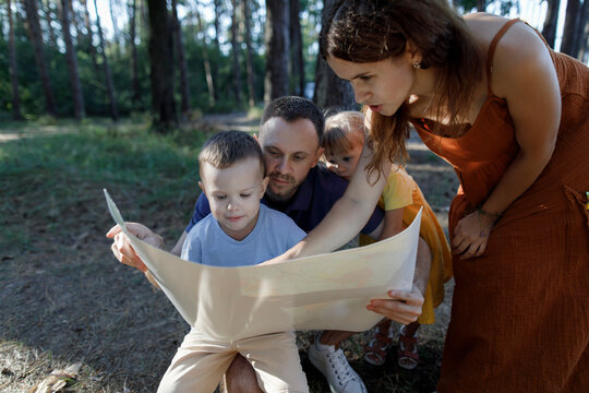 Parents with son and daughter reading map in forest