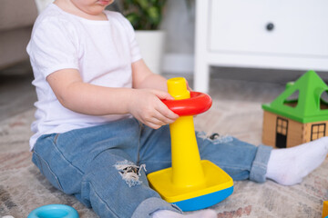 curly child girl playing with pyramid and constructor at home. early children development