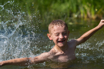 a boy bathes in a river in the summer on a hot day