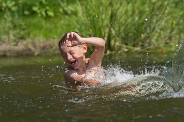 a boy bathes in a river in the summer on a hot day