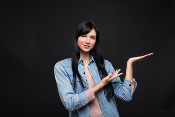 Attractive caucasian brunette girl in a shirt pointing with her hand to the palm with copy space...