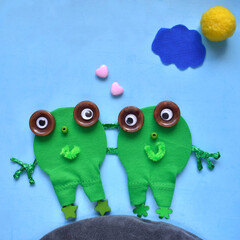 two frog friends made from different materials on a blue background for children, creativity and creativity of children