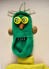 a cheerful green monster made of a knitted slipper, hair from ropes, eyes from plastic caps, teeth from beans, ears from plum seeds.