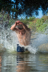 young man jumping into the river in the summer on a hot day