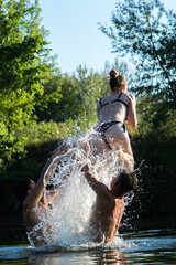 young girl jumping into the river in the summer on a hot day