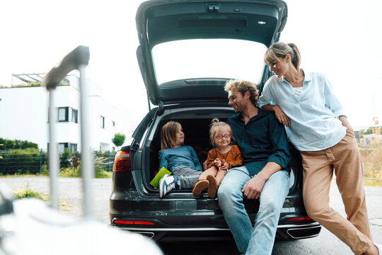 Smiling parents looking at children in car trunk on vacation