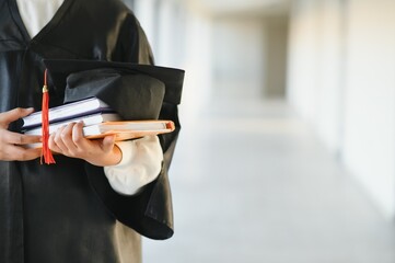 Happy Indian university student in graduation gown and cap holding diploma certificate.