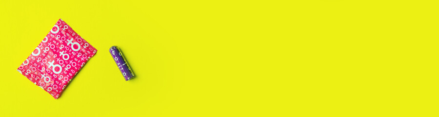Sanitary pad and tampon lie on yellow background. View from above. Gasket in red packaging. Tampon in purple packaging. Vertical image. Flatlay. Banner for insertion into site.