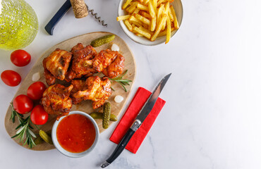 wood smoked chicken. Homemade wood smoked chicken legs with french fries and chili sauce on the side. Top view, on a white marble table top.