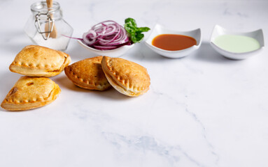 Homemade empanadas with sauces. South American street food. These delicious beef empanadas are mandatory to eat, they have a crunchy dough and an exquisite ground beef filling.