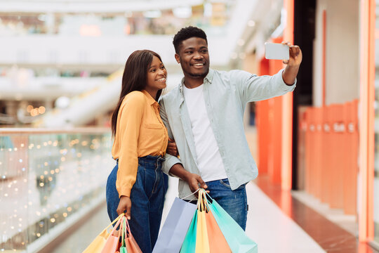 Happy black couple taking selfie after shopping at mall