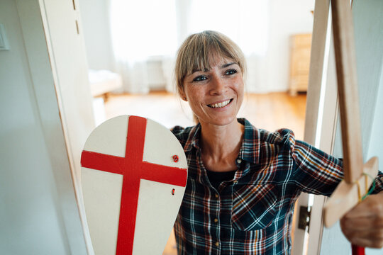 Smiling woman with sword and shield at home