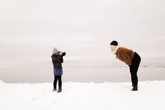 Daughter photographing mother through camera in winter