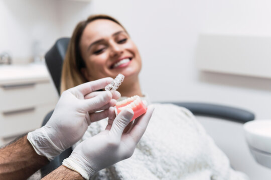 Dentist holding dentures by patient at medical room
