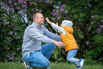 Son runing into father's arms. Man crouching at the park with his arms outstretched, with a boy running towards him.