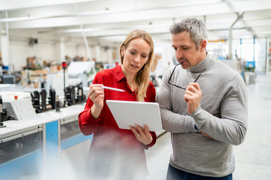 Blond businesswoman discussing over tablet PC with businesswoman in industry