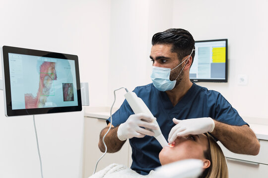 Dentist analyzing patient's teeth on intraoral scanner screen in clinic