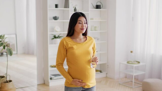 Body Hydration. Young Pregnant Asian Woman Drinking Water From Glass At Home