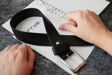 notebook with psychological trauma inscription and dark leather male belt as ptsd symbol on black...