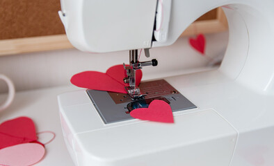 Sewing machine and paper hearts. The process of making a garland. Concept to sew with love, Valentines Day.
