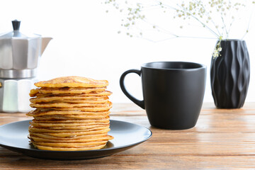Stack of pancakes, dark mug and coffee pot on wooden table Side view