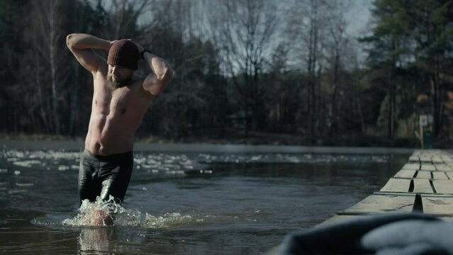 Caucasian adult man finishing swim in frozen lake. Shot with RED helium camera in 8K. 