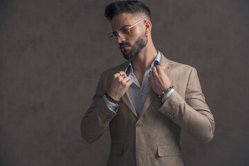 portrait of unshaved businessman with glasses arranging jacket