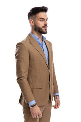 unshaved businessman in brown suit standing in line and looking to side