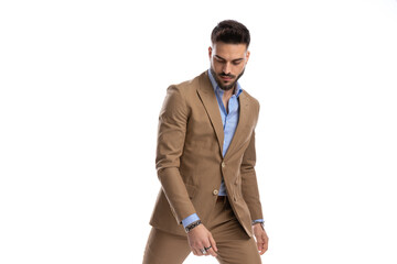 bearded businessman in brown suit looking down and posing