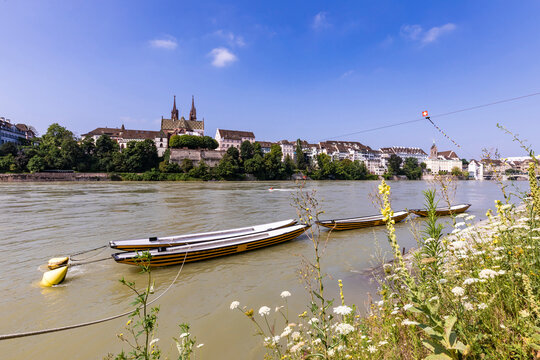 Switzerland, Basel-Stadt, Basel, Rowboats moored on bank of Rhine river in summer with city buildings in background