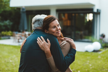 Woman with eyes closed hugging man at backyard