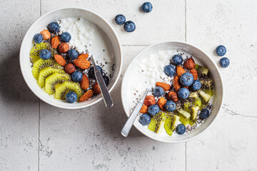 Breakfast cottage cheese with berries, nuts and chia seeds in white bowl.