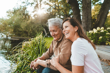 Cheerful woman sitting with senior man by lake
