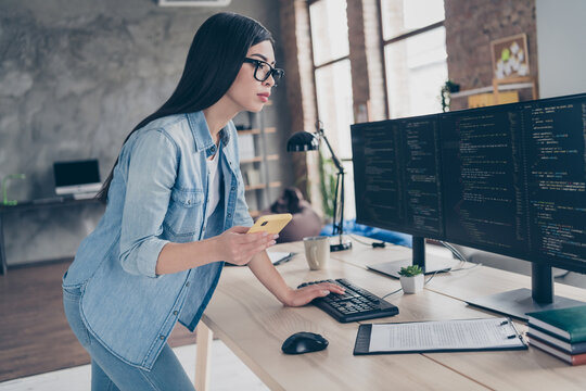 Profile side view portrait of attractive focused skilled girl expert web designer using gadget editing css source at workplace workstation indoors