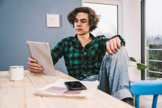 Young student holding tablet PC E-learning at home