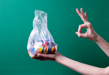 a woman's hand holds a bag with plastic lids for recycling