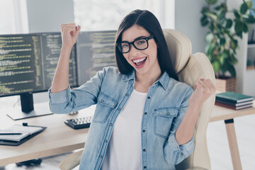 Photo of skilled lady editor sit desk fist up celebrate solving error optimization in workplace...