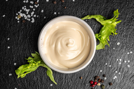 Bowl with tasty white sauce on dark background. Food recipe background. Close up
