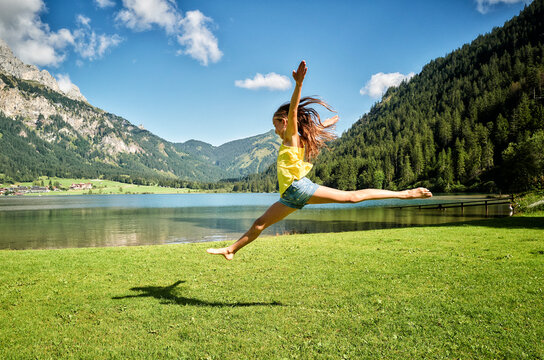Girl jumping and doing splits in air at Haldensee lakeshore