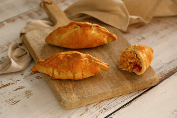 Traditional spanish food: Delicious empanadas stuffed with tuna, tomato and onion on rustic background