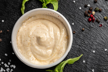 Bowl with garlic sauce on dark background. Food recipe background. Close up