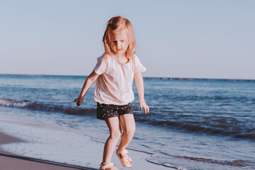 Fototapeta na wymiar Cute toddler little girl wear casual clothes playing on sandy beach.