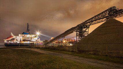 Fototapeta na wymiar Anchored barge at night ready for unloading gravel, Port of Antwerp.