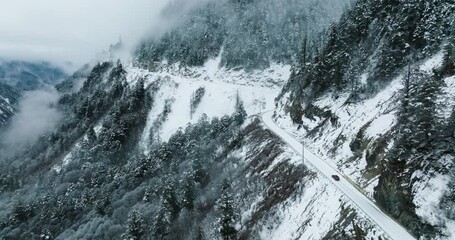 Aerial view of red car driving on a snowy mountain road , winter travel landscape - Powered by Adobe