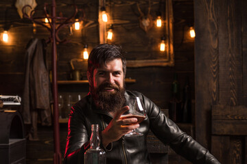Man with beard holds glass brandy. Bearded drink cognac. Expensive drink. Man in shirt drinking brandy or cognac. Sexy young man with glass of whiskey. - obrazy, fototapety, plakaty