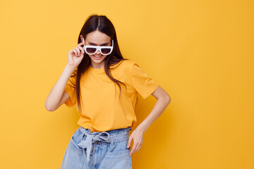 beautiful girl with long hair wearing sunglasses posing yellow background