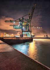 Night scene with gigantic crane on illuminated container terminal, Port of Antwerp, Belgium.