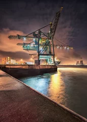 Gordijnen Night scene with gigantic crane on illuminated container terminal, Port of Antwerp, Belgium. © tonyv3112