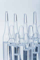 Glass medical ampoule vial for injection. Medicine is dry white drug penicillin powder or liquid with of aqueous solution in ampulla. Close up. Bottles ampule with aluminum cap on backgrounds gray.