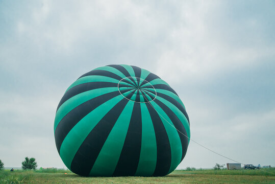 Inflating, unpack and flying up hot air balloon watermelon. Burner directing flame into envelope. Take off aircraft fly in morning blue sky. Start hot air burning to inflate gas fire to air balloon.